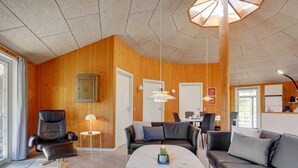 Een moderne woonkamer met houten details, een marmeren salontafel, leren banken en een eetgedeelte met uitzicht.