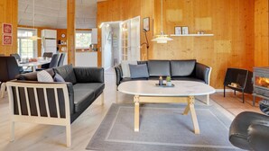 Een moderne woonkamer met houten inrichting, een ronde salontafel en een open haard.