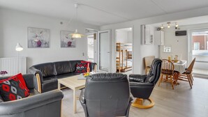Uma sala de estar moderna com um sofá de couro preto, uma mesa de jantar de madeira e uma poltrona de couro preto.