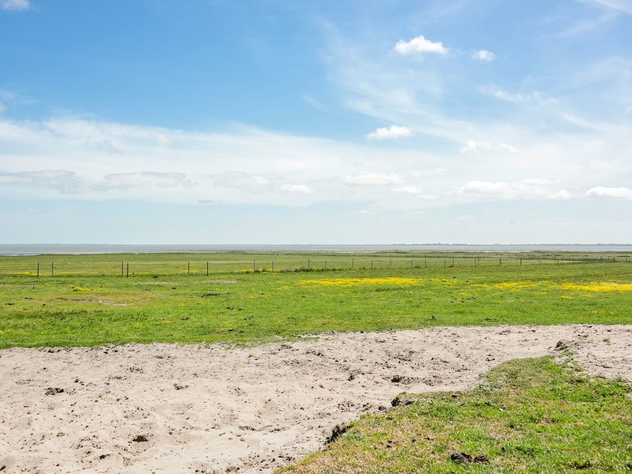 Un extenso campo abierto con una cerca al frente y un horizonte plano a lo lejos.