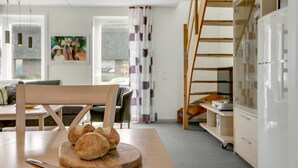 Une cuisine moderne avec une table en bois, une planche à découper avec du pain et un couteau.