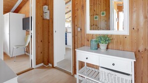 Ein Zimmer mit Holzwandverkleidung, einem weißen Konsolentisch, einem Spiegel und einer Zimmerpflanze.