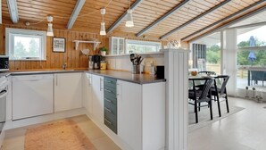 Eine moderne Küche mit Holzbalken, weißen Schränken und einer zentralen Kochinsel.