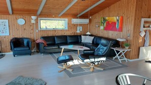 A modern living room with a sectional sofa, a small round table, and a black leather chair.