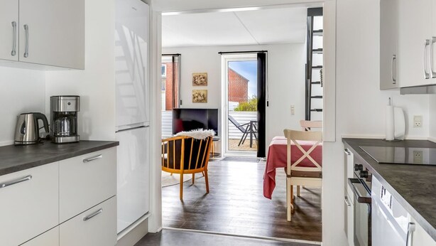 Una cucina moderna con mobili bianchi, una macchina da caffè e un'area pranzo con tavolo e sedie.