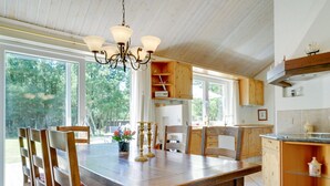 Ein Essbereich mit Holztisch und Stühlen, einer Chandelier und Blick ins Freie.