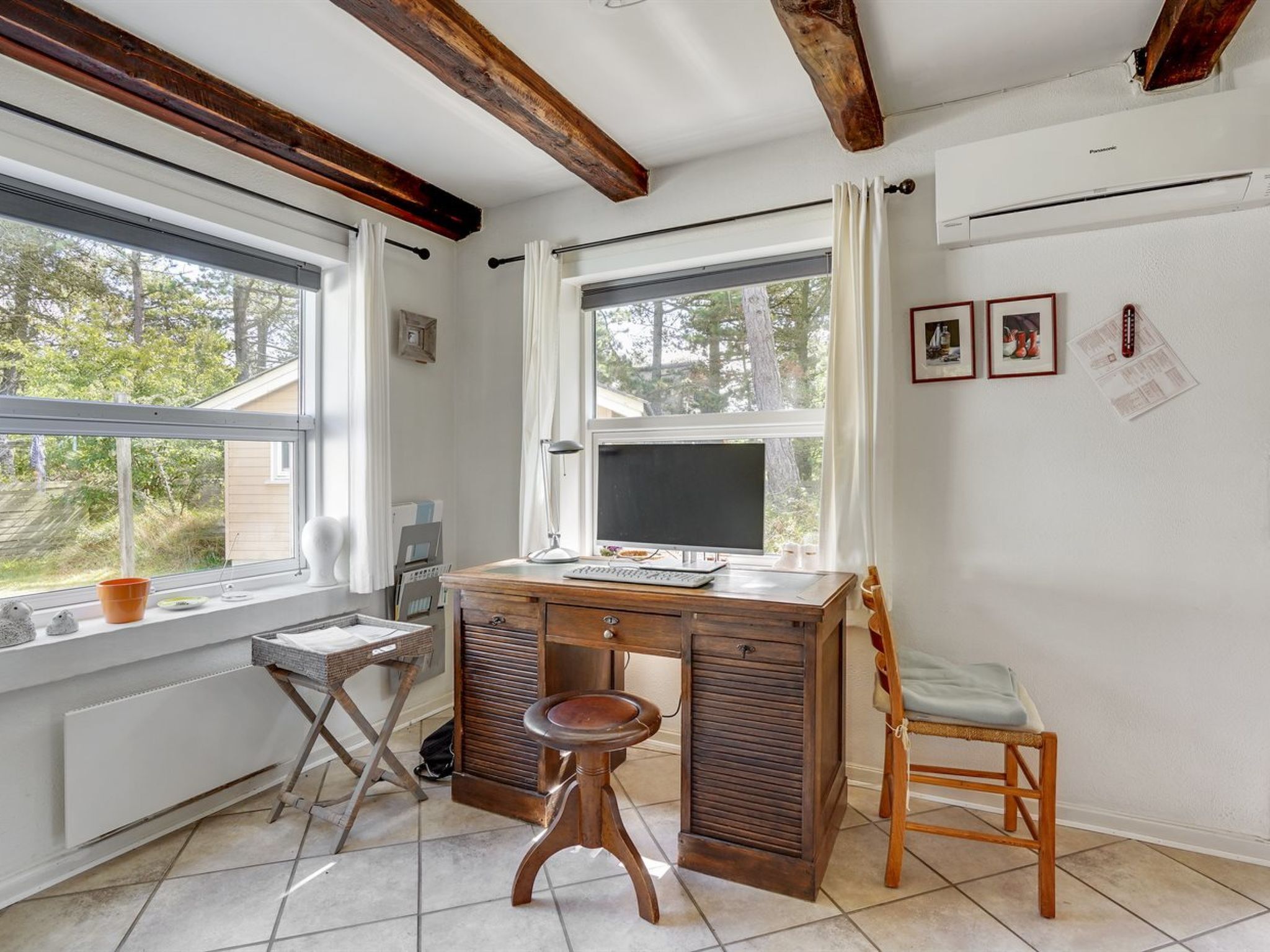 A room with a desk, chair, and a window overlooking a garden.