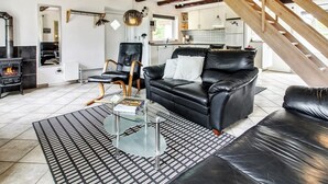 Een moderne woonkamer met een zwarte leren bank, een glazen salontafel en een open haard.