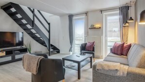 Ein modernes Wohnzimmer mit Treppe, Sofa, Couchtisch und Fernseher.