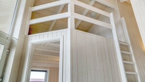 Une pièce aux hauts plafonds, avec des poutres apparentes en bois et une échelle menant à une mezzanine.