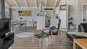 Un salon moderne doté d’un téléviseur à écran plat, d’un coin repas, d’une cuisine et d’un espace salon confortable avec une cheminée.