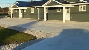 A row of single-story houses with attached garages, a gravel driveway, and a utility pole in the background. - Great little getaway  (Port Hastings)