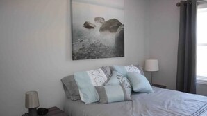 A bedroom with a bed, pillows, a bedside table with a lamp, and a wall-mounted artwork. - Great little getaway  (Port Hastings)
