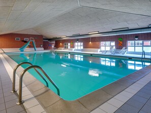Ein Hallenbad mit Rutsche, Fliesenboden und Backsteinwänden.