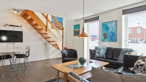 A modern living room with a wooden staircase, a black leather sofa, a glass coffee table, and a TV on a white stand. - "Mahena" - 2.3km from the sea by Interhome (Rømø)
