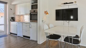 A modern kitchen with white cabinets, a built-in oven, and a dining area with a white table and black chairs. - "Mahena" - 2.3km from the sea by Interhome (Rømø)