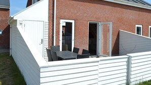 A single-story brick house with a white exterior, a covered patio with a table and chairs, and a garage door with the number 59. - "Mahena" - 2.3km from the sea by Interhome (Rømø)