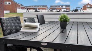Een terras met een tafel, stoelen, een bloempot en een boek.