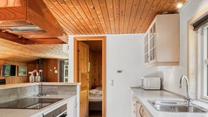 Une cuisine compacte avec un plafond en bois, un four encastré, un évier et un grille-pain.