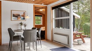 Un espace repas moderne avec un plafond en bois, un mur en briques blanches et une grande fenêtre.