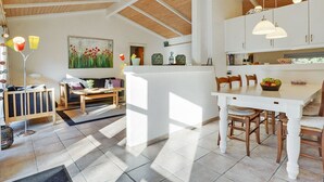 Un vaste espace de vie doté d’un plafond haut, d’une table à manger avec des chaises, d’un canapé et d’une bibliothèque.