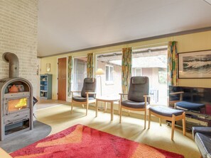 Ein gemütliches Wohnzimmer mit Kamin, bequemen Sitzgelegenheiten und großen Fenstern.