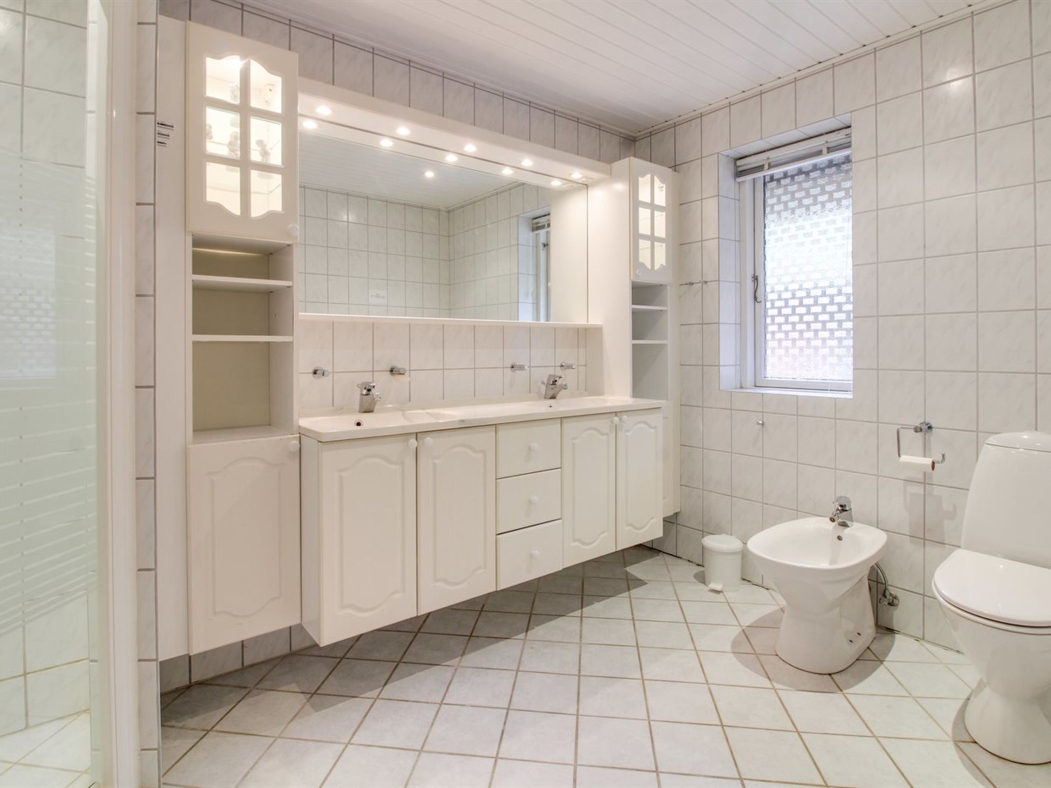 A modern bathroom with a large vanity, a toilet, and a bidet.