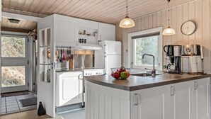 Een moderne keuken met witte kasten, een centraal eiland, roestvrijstalen apparatuur en hanglampen.