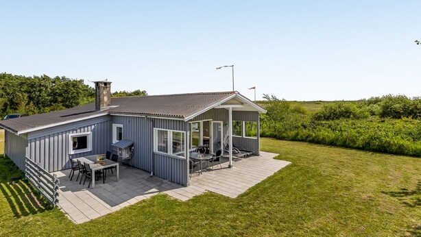 Et moderne hus med terrasse, skorsten og lille træterrasse.