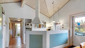 A kitchen with a central island, white walls, and a tiled floor. There are hanging lights, a microwave, and a refrigerator. - "Asdis" - 2.8km from the sea by Interhome (Rømø)