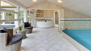 Ein Poolbereich im Innenbereich mit einer Rezeption, Korbmöbeln und Fliesenboden.