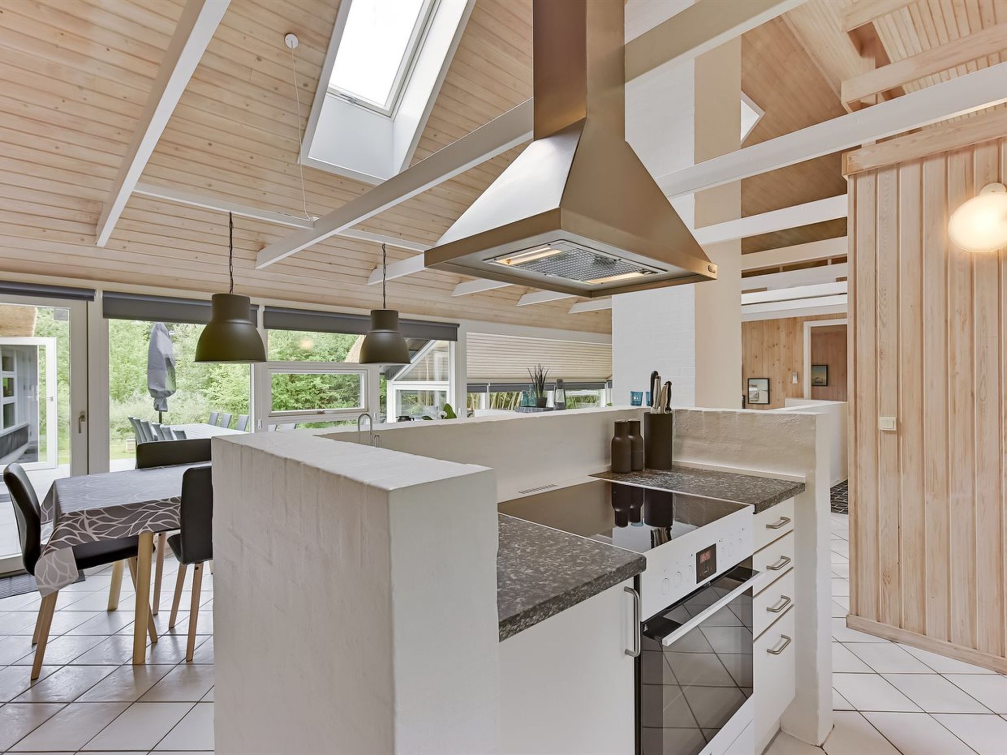 A modern kitchen with a central island, built-in oven, and pendant lighting.