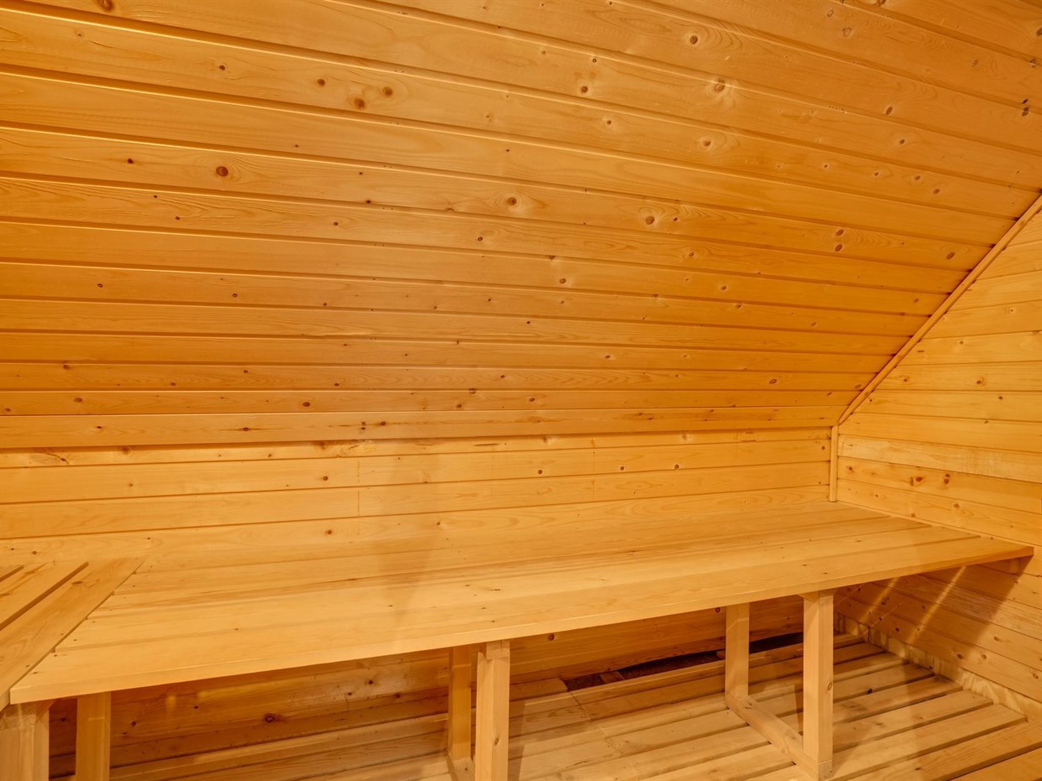 Interior de madera con un banco y techo inclinado.