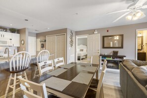 A modern living room with a dark wood dining table, white chairs, a gray sofa, and a ceiling fan. - Pondview Cityscape - Best of Branson! (Branson)