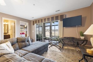 A living room with a sectional sofa, a flat-screen TV, a coffee table, and a dining area with a table and chairs. - Pondview Cityscape - Best of Branson! (Branson)