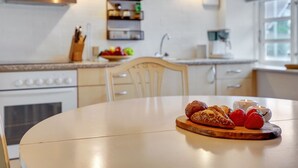 Eine Küche mit weißen Schränken, einer Holzauskładfläche und einem Esstisch mit Brot und Erdbeeren.