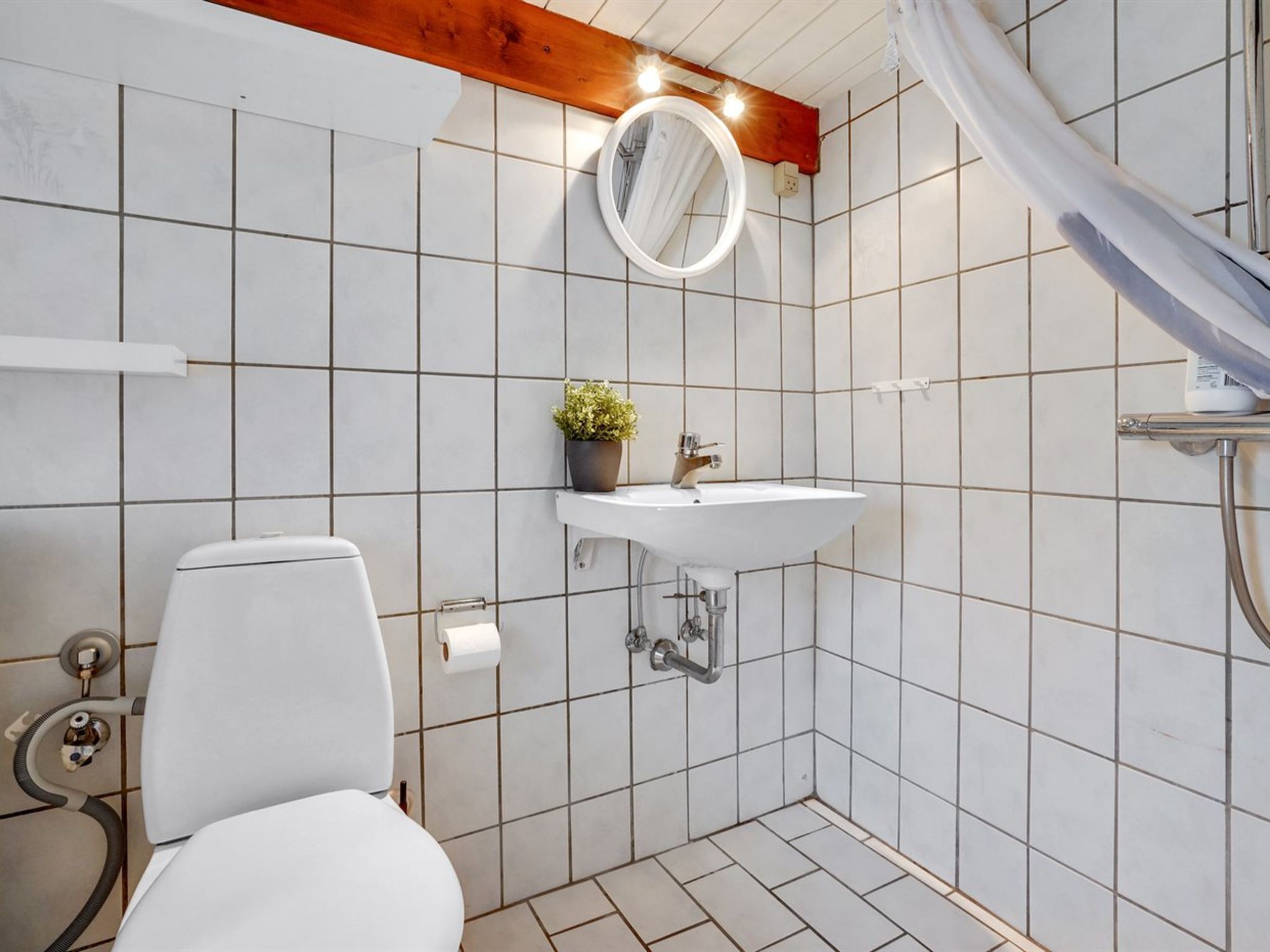 A bathroom with a white toilet, a sink with a mirror above it, and a shower area.