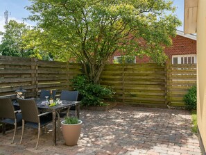 A patio area with a table and chairs, surrounded by a wooden fence and a brick wall.