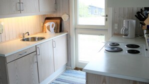 Una cocina compacta con muebles de madera, un lavamanos, una cafetera y una estufa.