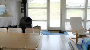 Una habitación acogedora con una mesa de madera, sillas, chimenea y ventanas amplias.