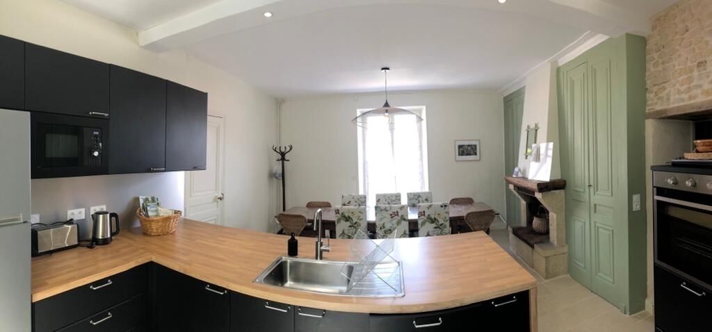 A modern kitchen with black cabinets, a wooden countertop, a built-in microwave, and a large island with a sink.