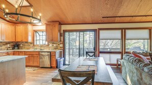 A spacious kitchen with wooden cabinets, a large island, and a dining area with a long table and chairs. - Deck & Gas Grill: Secluded Arnold Cabin Rental! (Arnold)