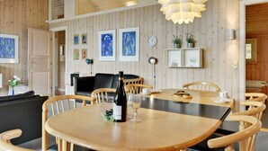 A dining area with a wooden table and chairs, a bottle of wine, and a clock on the wall. - "Nanne" - 1km from the sea by Interhome (Fanø)
