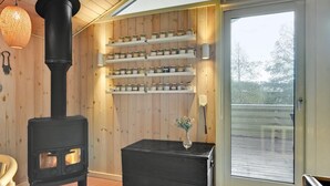 A cozy room with a wood-burning stove, shelves with jars, a vase with flowers, and a view through a glass door. - "Nanne" - 1km from the sea by Interhome (Fanø)