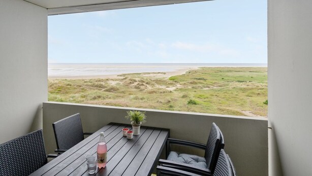 A balcony with a table and chairs, a potted plant, and a bottle. - "Edelina" - 50m from the sea by Interhome (Fanø)