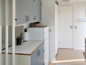 Een koelkast, een vaatwasser, kookgerei, borden en bestek