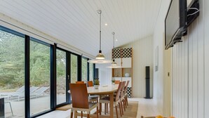 Ein moderner Essbereich mit großem Tisch, Stühlen und Obstschale.