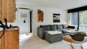 Ein gemütliches Wohnzimmer mit einem grauen Sofa, einem Holzschrank und einem Schaukelstuhl.