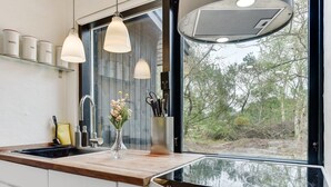 Eine moderne Küche mit einem großen Fenster, Edelstahlgeräten und Pendelleuchten.