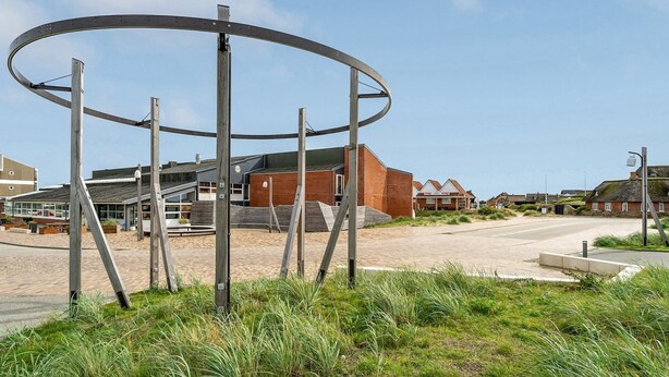 A modern building with a circular metal structure in the foreground.